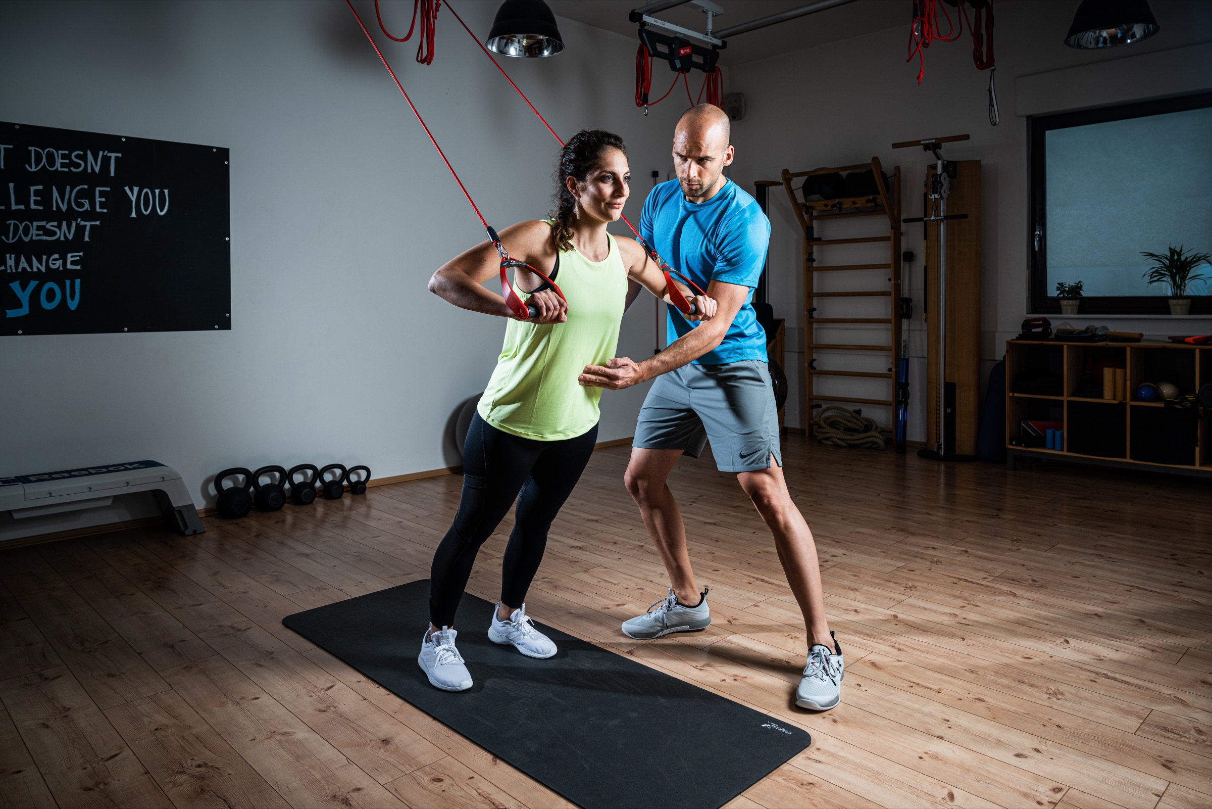 A practitioner guiding a client through a Redcord movement exercise
